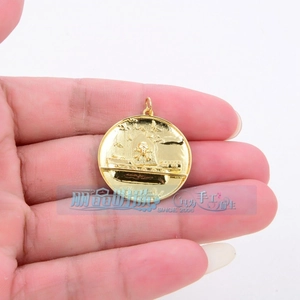 Macro view of a gold-plated circular pendant featuring an embossed pirate ship pattern