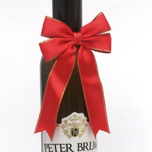 Detail of red satin bow with gold stitching on a dark green bottle for gift decor