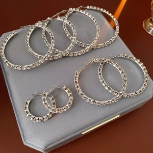 Three sizes of silver hoop earrings with full rhinestones on velvet display box