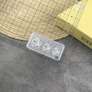 Close-up of clear silicone hibiscus flower nail art mold with ruler for scale measurement