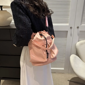 Détail du sac seau rose en nylon avec cordon et poches latérales porté par un mannequin