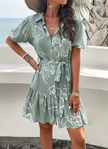 Close-up of green and white geometric print dress with button front and waist tie detail