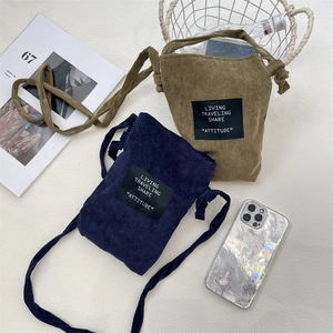 Flat lay of vintage corduroy mini crossbody bags in navy and tan with decorative labels