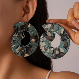 Vue détaillée de grandes boucles d'oreilles créoles en tissu camouflage portées par un mannequin