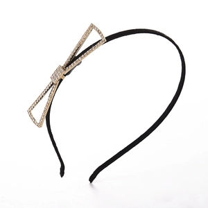 Black thin headband with elegant gold metal bow and sparkling rhinestones on white background