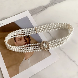 Detail of elegant white multi-layer pearl belt with a sparkling rhinestone buckle decoration