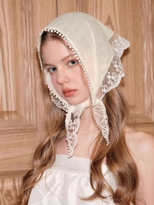 Detail of vintage white lace headscarf with floral embroidery and tassel fringe edges