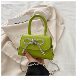 Macro detail of vibrant green leather mini bag with a sparkling rhinestone bow