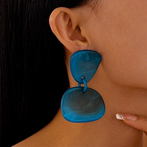Gros plan de boucles d'oreilles en acrylique bleu marbré au design géométrique irrégulier