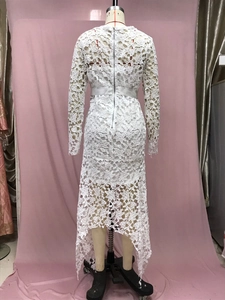Macro detail of white lace hollow-out floral pattern on long sleeve asymmetric dress