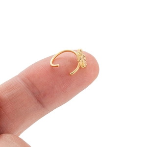 Golden hoop nose ring featuring zircon inlaid leaf design shown on a fingertip