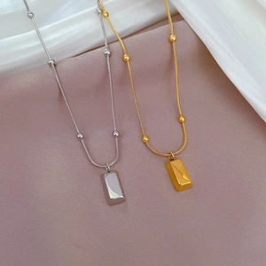 Detail of silver and gold titanium steel snake chains with rectangular bar pendants