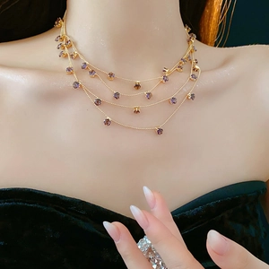 Détail d'un collier doré multicouche avec zircons violets porté par le mannequin