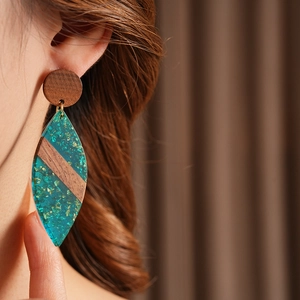 Détail de la boucle d'oreille en bois et résine sarcelle avec feuille d'or sur modèle