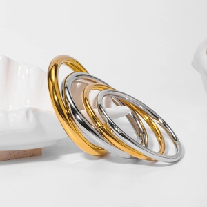Three minimalist stainless steel hollow bangles in gold silver and rose gold finishes