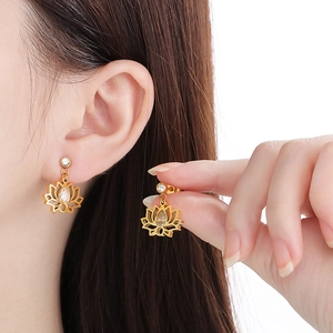 Boucles d'oreilles lotus dorées avec pétales creux et zircon sur un mannequin