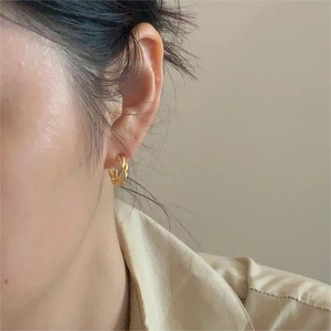 Classic golden twisted rope hoop earrings worn by a model for a minimalist daily style