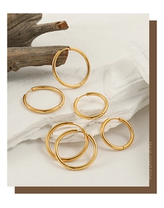 Macro shot of five gold minimalist stainless steel hoop earrings in various sizes