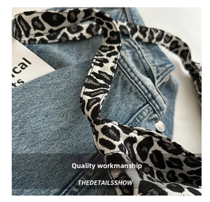 Close-up of denim canvas bag with leopard print woven strap and neat stitching details