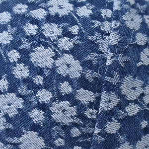 Close-up of dark blue denim fabric with white floral pattern and twill texture detail