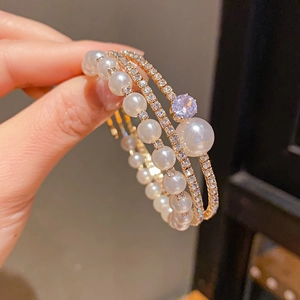 Close-up of multi-layer bracelet featuring white pearls and zircon-encrusted gold bands