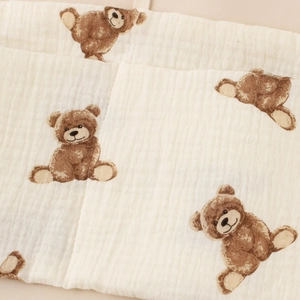 Close-up of cotton muslin baby crib organizer with brown bear print and soft texture