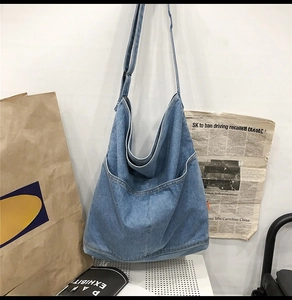 Detail view of large denim hobo bag featuring wide exterior pockets and soft wash texture