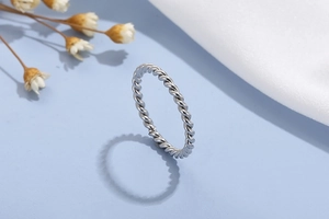 Macro shot of silver twisted rope ring detail standing on light blue background