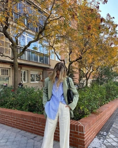 Outdoor street shot of women's lime green V-neck blazer with blue striped shirt and pants