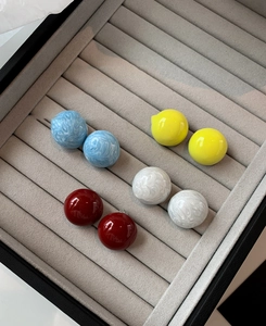 Détail de boucles d'oreilles boules géométriques colorées dans un écrin en velours