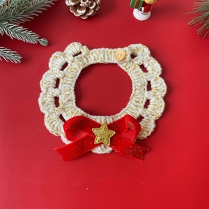 Detail of Christmas cat crochet collar with red bow and gold star on festive background