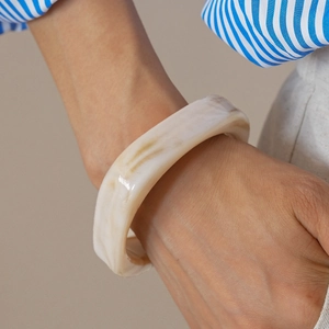 Close-up of a wide resin bangle with marble texture worn on wrist for a chic retro look
