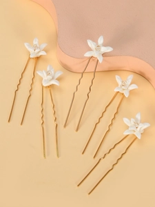 Close-up of five white ceramic flower hair pins with crystal centers and gold prongs