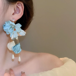 Detail of fabric flower earrings with faux pearl tassels and gold chains on model