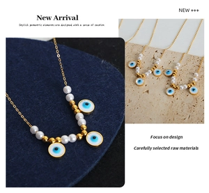 Detail of gold evil eye necklace with white pearls and blue enamel pendants on felt