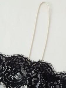 Nahaufnahme der schwarzen Wimpernspitze und des dünnen weißen Schultergurts am Kleid