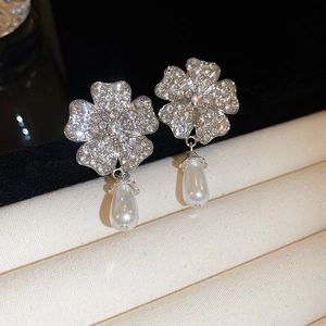 Macro detail of silver floral earrings with sparkling rhinestones and drop pearls