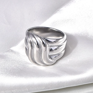 Détail macro d'une bague ondulée en acier titane sur un élégant tissu de soie blanche