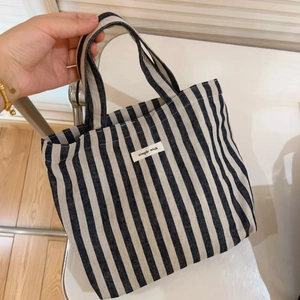 Detailed view of striped canvas tote bag featuring a stitched Simple Wish logo label