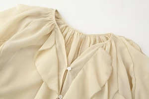 Detailed view of apricot V-neck blouse featuring ruffled collar and button-down stitching