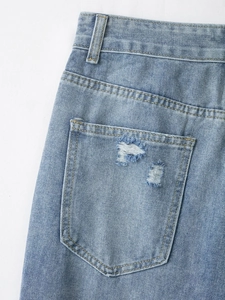 Dettaglio della vita e della tasca posteriore di jeans blu chiaro con strappi decorativi