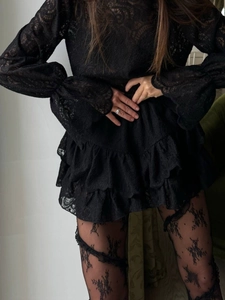 Detail of elegant black sheer lace long sleeves and tiered ruffle hem on a dress