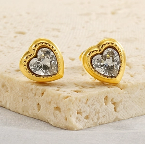 Macro view of gold heart stud earrings featuring a large clear heart-shaped zircon