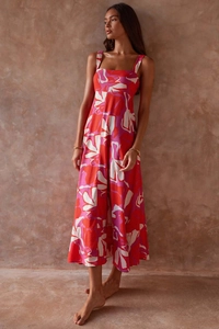 Detailed close-up of a floral print sleeveless dress with a square neckline on a textured wall