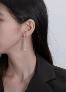 Detail of geometric silver drop earrings with white zircons on a professional model