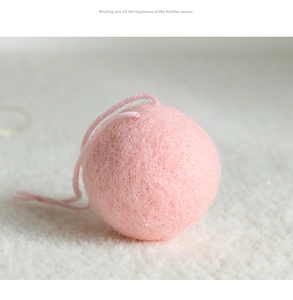 Macro shot of pink wool felt Christmas ball ornament with hanging loop on soft plush rug