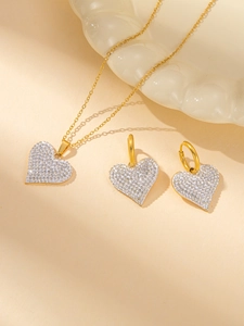 Detailansicht des Herz-Schmucksets in Gold mit Diamanten auf weißem Wellentablett