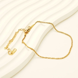 Detail of 18K gold plated sparkling anklet with adjustable extension and clasp on white surface