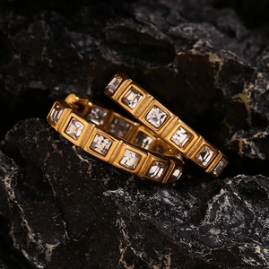 Macro shot of 18K gold plated earrings with micro-set square zircons on black rock