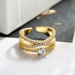 Elegant gold plated crisscross ring with zircons and center stone on a white background